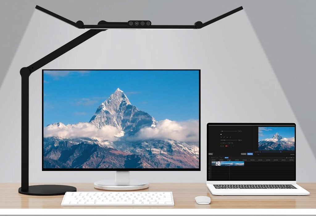 A desk lamp illuminates a multi-screen workspace with a monitor and laptop, showcasing a setup ideal for Desk Lamps for Graphic Designers.
